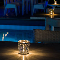 Elegant crystal candle holder with warm golden light against a serene blue background, perfect for ambiance.