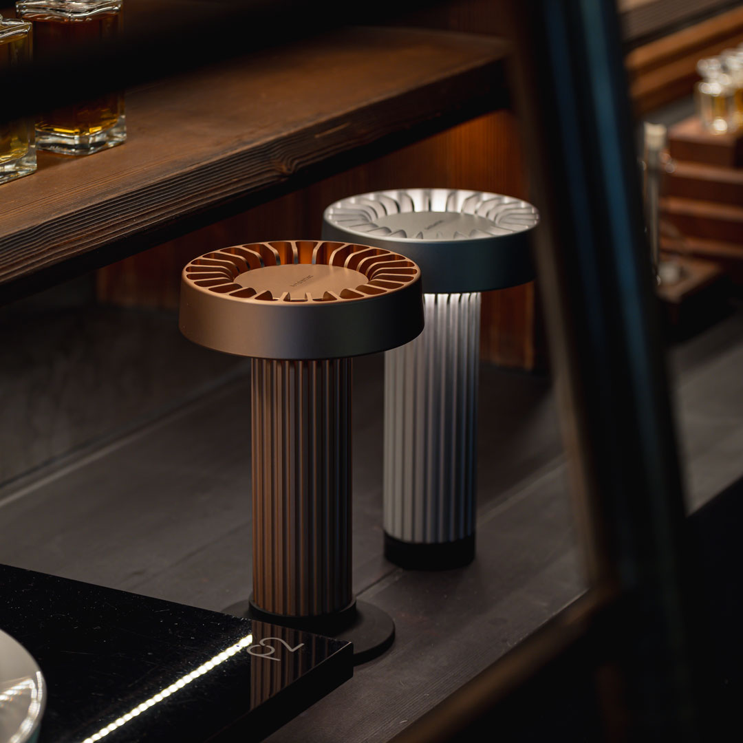Brown and silver decorative lamps with ribbed bases, set against a dark wood backdrop. Modern and stylish design.