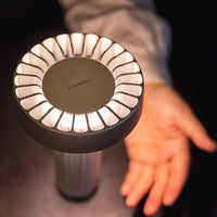 "Modern lamp with a sleek black base and illuminated white circular pattern, creating a warm ambiance."