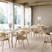 Light wood tones, soft white elements, and neutral beige walls create a cozy, modern dining space.