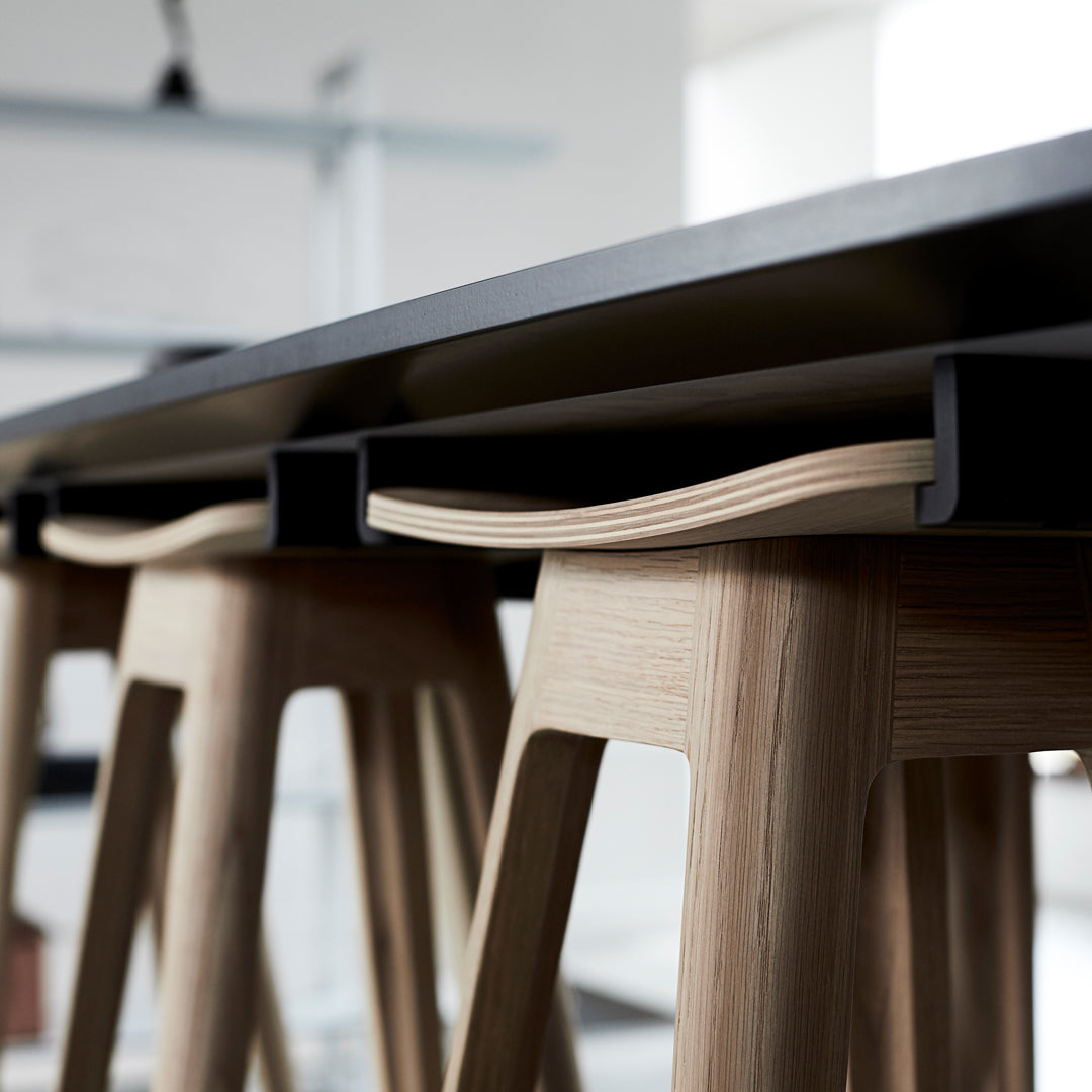 Light wood stools with minimalist design, paired with a sleek black countertop, showcasing natural grain and smooth finish.