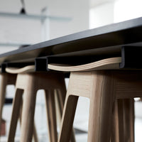 Light wood stools with minimalist design, paired with a sleek black countertop, showcasing natural grain and smooth finish.