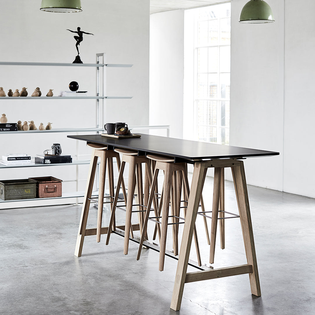Black tabletop with natural wood legs, minimalist design in a modern, airy space; neutral colors and clean lines.