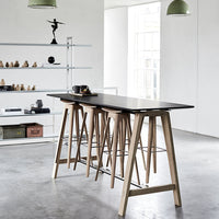 Black tabletop with natural wood legs, minimalist design in a modern, airy space; neutral colors and clean lines.