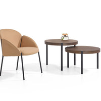 Tan upholstered chair with sleek black legs and two round wooden tables in rich brown tones. Modern minimalist design.