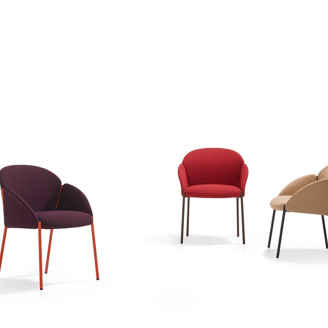 Three chairs in burgundy, red, and beige with sleek, colorful metal legs against a white background.