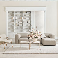 Light beige sofas and armchair with soft white accents, accompanied by a pastel floral arrangement on a neutral rug.
