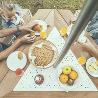 "Stylish outdoor dining setup featuring beige, white, and vibrant yellow accents on a geometric tablecloth."