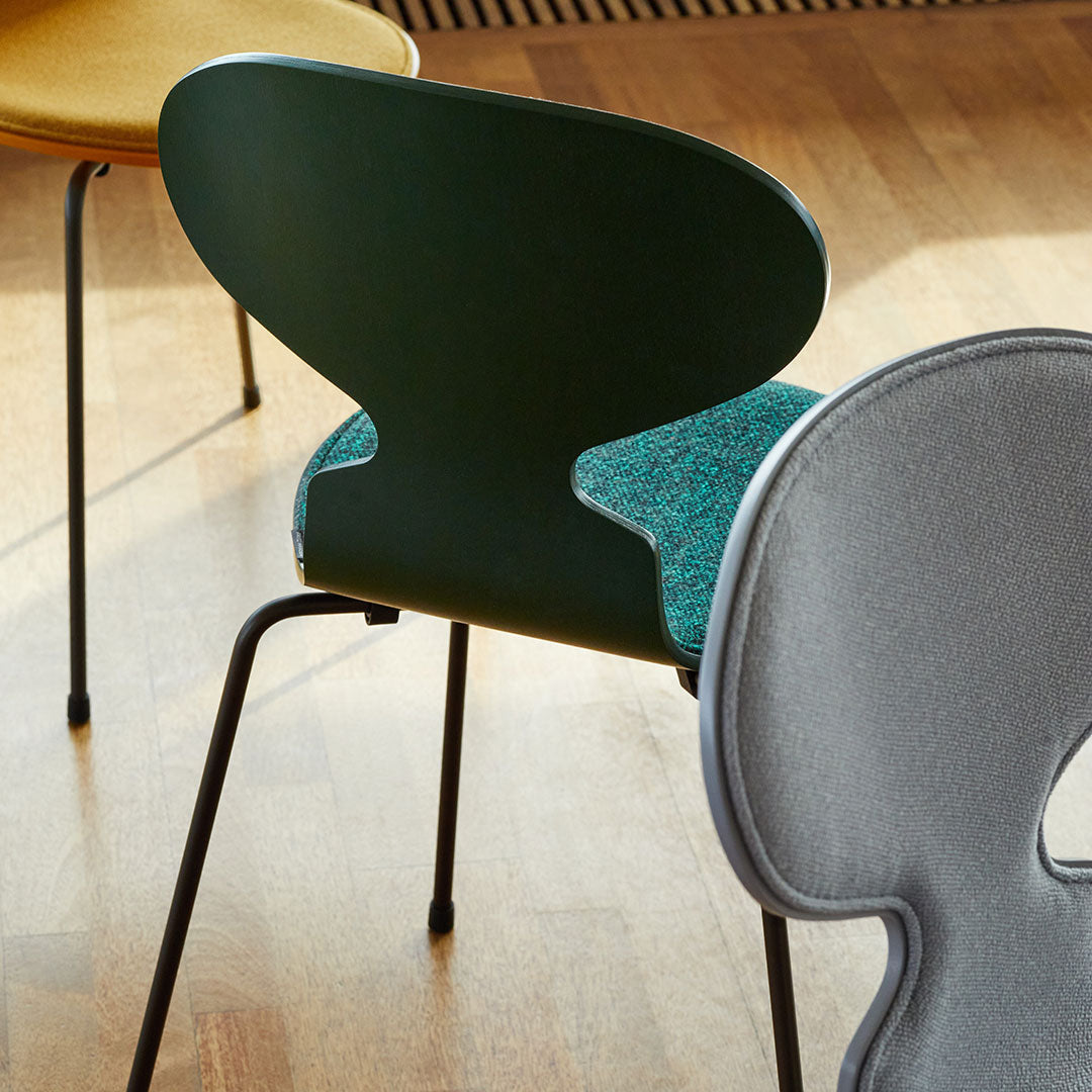 "Colorful chairs featuring green, yellow, and gray tones with unique patterns and textures on a wooden floor."
