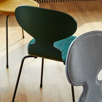 "Colorful chairs featuring green, yellow, and gray tones with unique patterns and textures on a wooden floor."