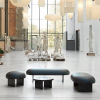 Modern black furniture with smooth curves, featuring a glossy finish and minimalist design in a spacious gallery setting.