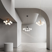 Modern pendant lamps with white globes and elegant brass accents in a minimalist gray architectural space.