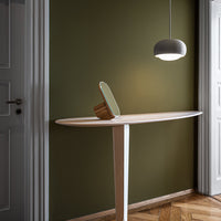 Green wall backdrop with a sleek white table and light, featuring a curved design and natural wood accents.