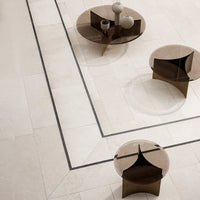 Light beige tile with a black border, featuring two modern glass tables in warm brown tones and minimalist decor.