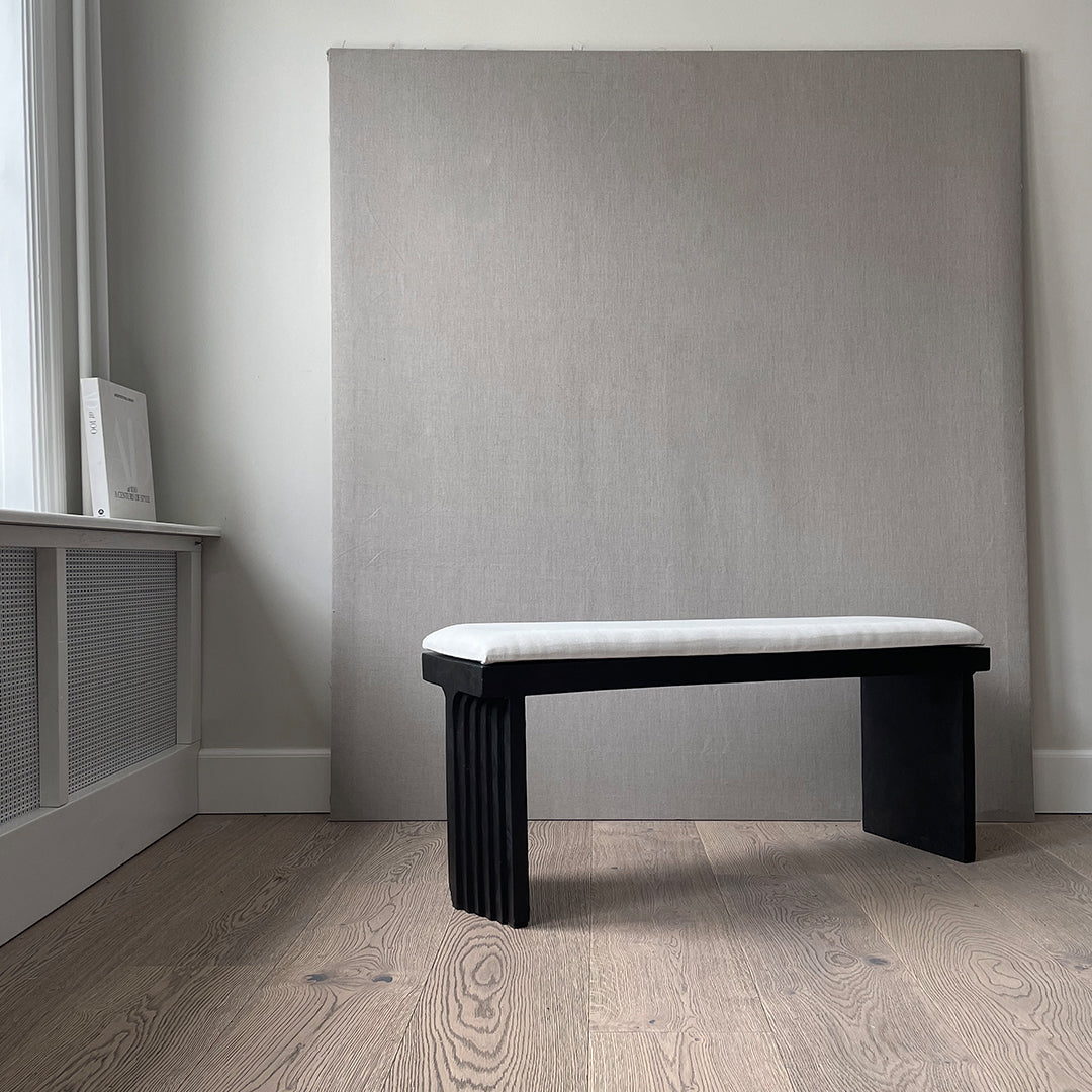 Black and white bench with a textured seat, against a neutral gray backdrop. Modern minimalist design.