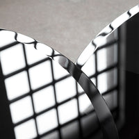 "Close-up of smooth metallic curves reflecting light, with a contrasting dark surface and geometric shadow patterns."