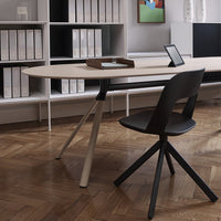 Modern oval desk in soft beige with a contrasting black chair, set against a sleek, minimalistic background.