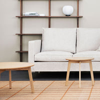 Light beige sofa with soft fabric, paired with light wood tables on a geometric patterned rug with orange lines.