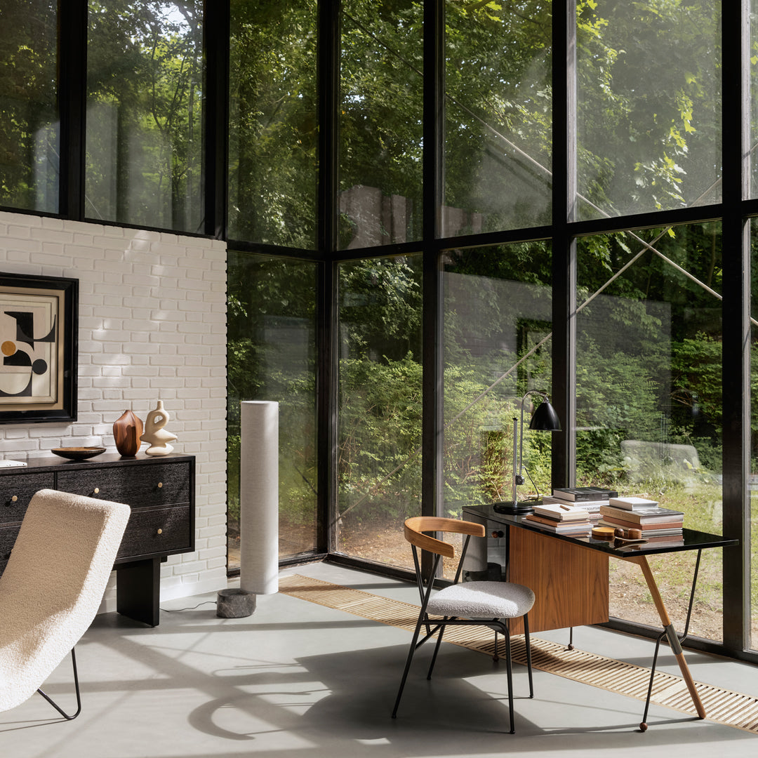 Modern workspace featuring neutral tones, geometric patterns, and large glass windows showcasing green outdoors.