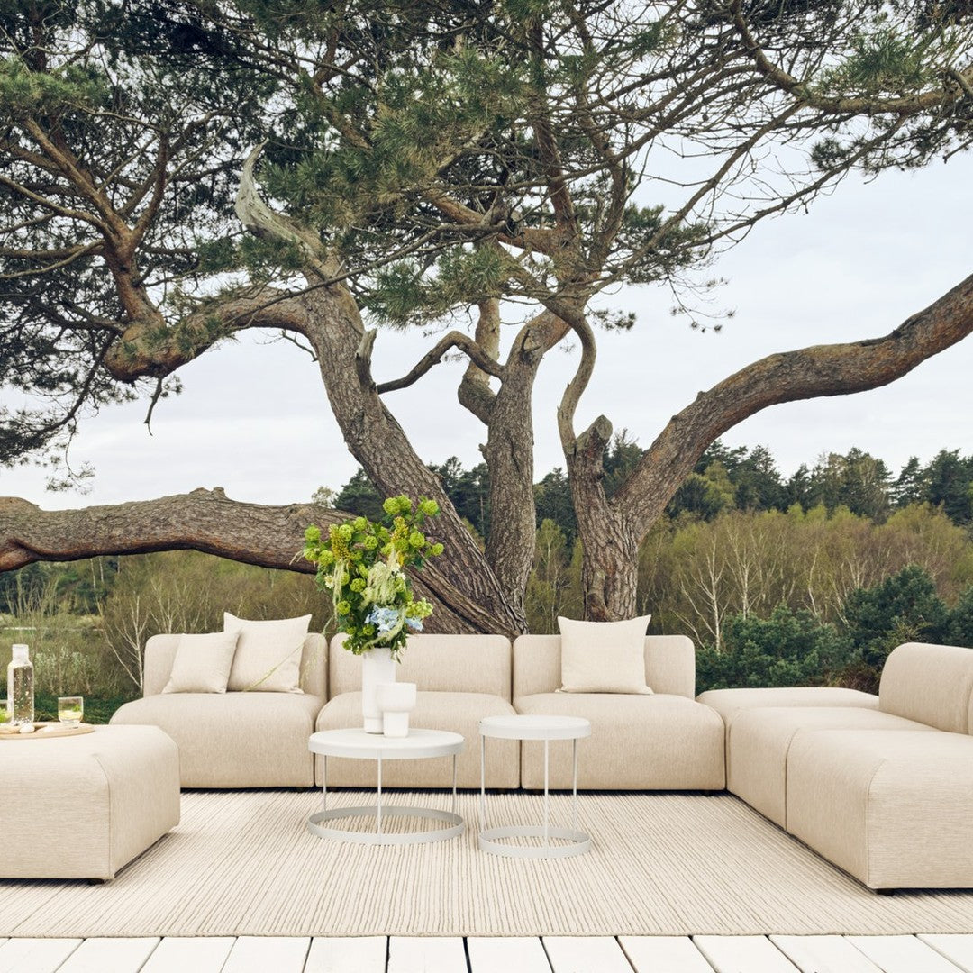 Beige sectional sofa with smooth lines, soft textures, and minimalistic design, set against a natural outdoor backdrop.