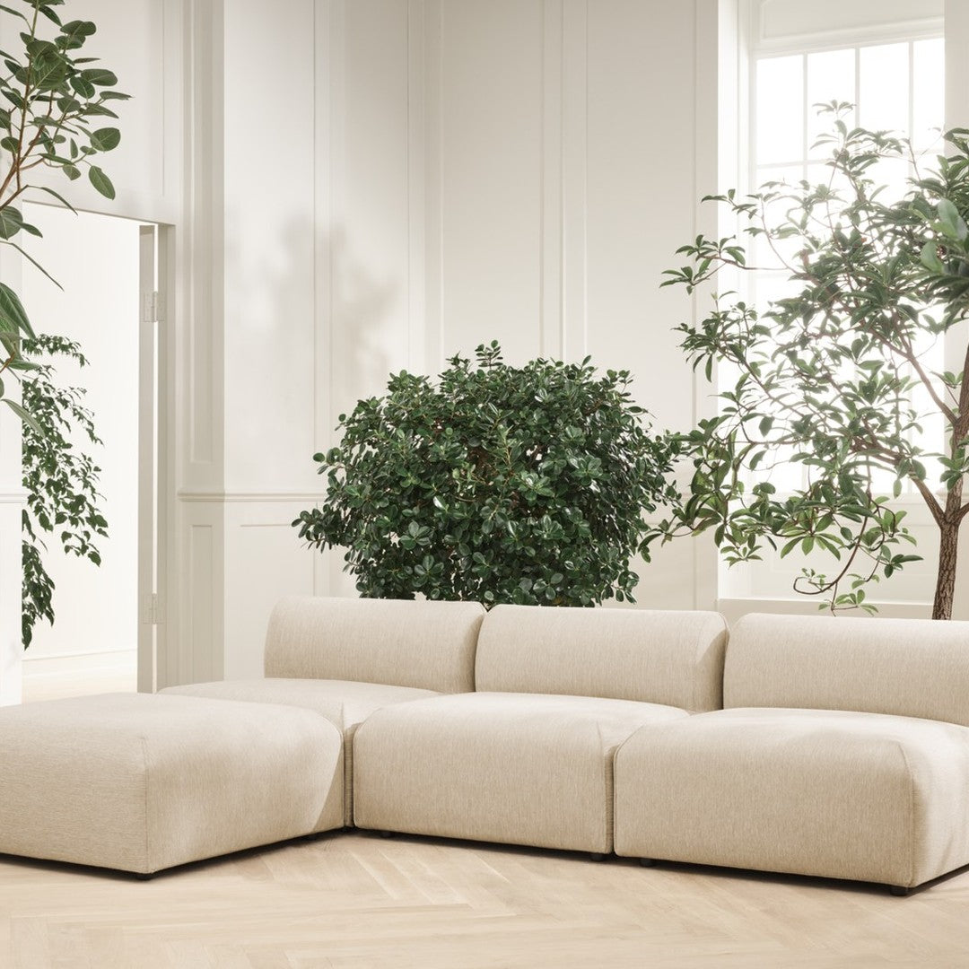 Beige modular sofa with soft, textured upholstery, complemented by lush greenery in a bright, minimalist setting.