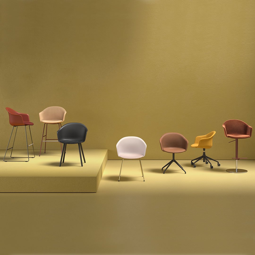 Stylish chairs in shades of pink, brown, yellow, black, and cream against a warm yellow background. Modern design patterns.