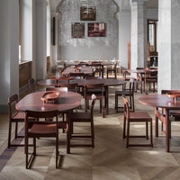 Round wooden tables and chairs in rich maroon hues, set against light gray and patterned flooring.
