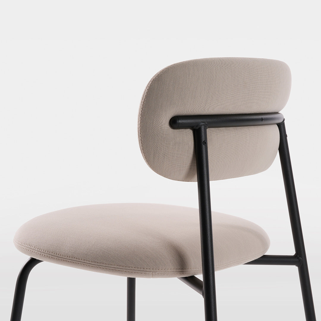 Light beige upholstered chair with a smooth texture and minimalist black metal frame. Elegant and modern design.