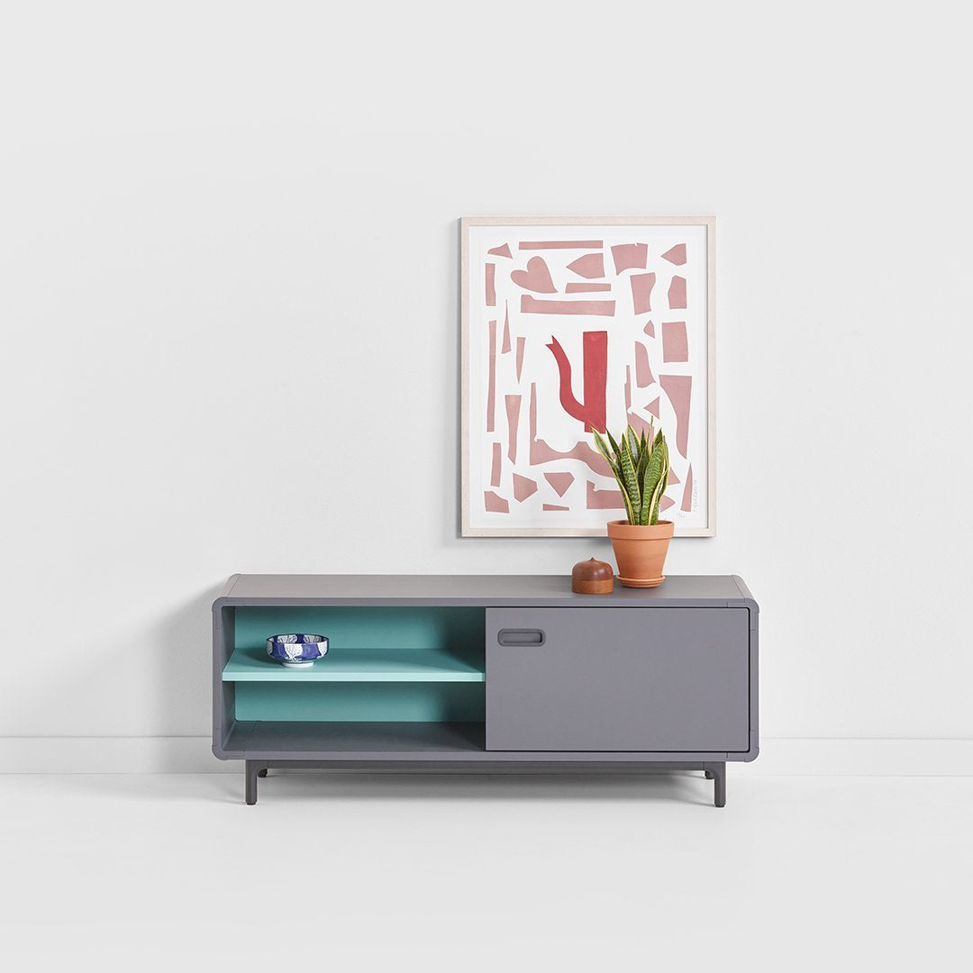 Modern gray TV stand with teal accents, complemented by a pink and white abstract art piece above.