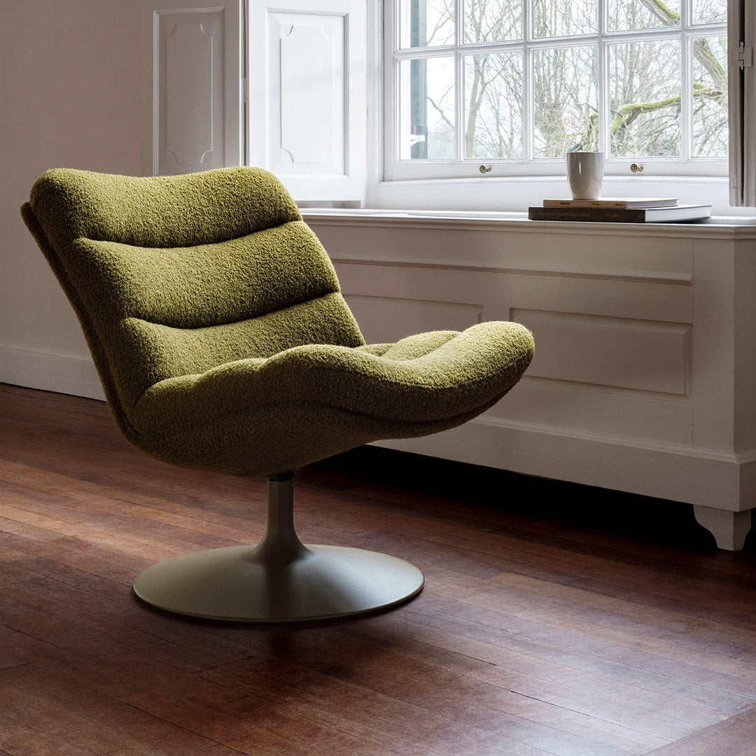 Lime green curvy swivel chair with plush texture, set against a warm wooden floor and bright window backdrop.