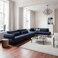Navy blue sectional sofa with minimalist patterns, paired with a white accent chair and geometric rug on warm wooden floor.