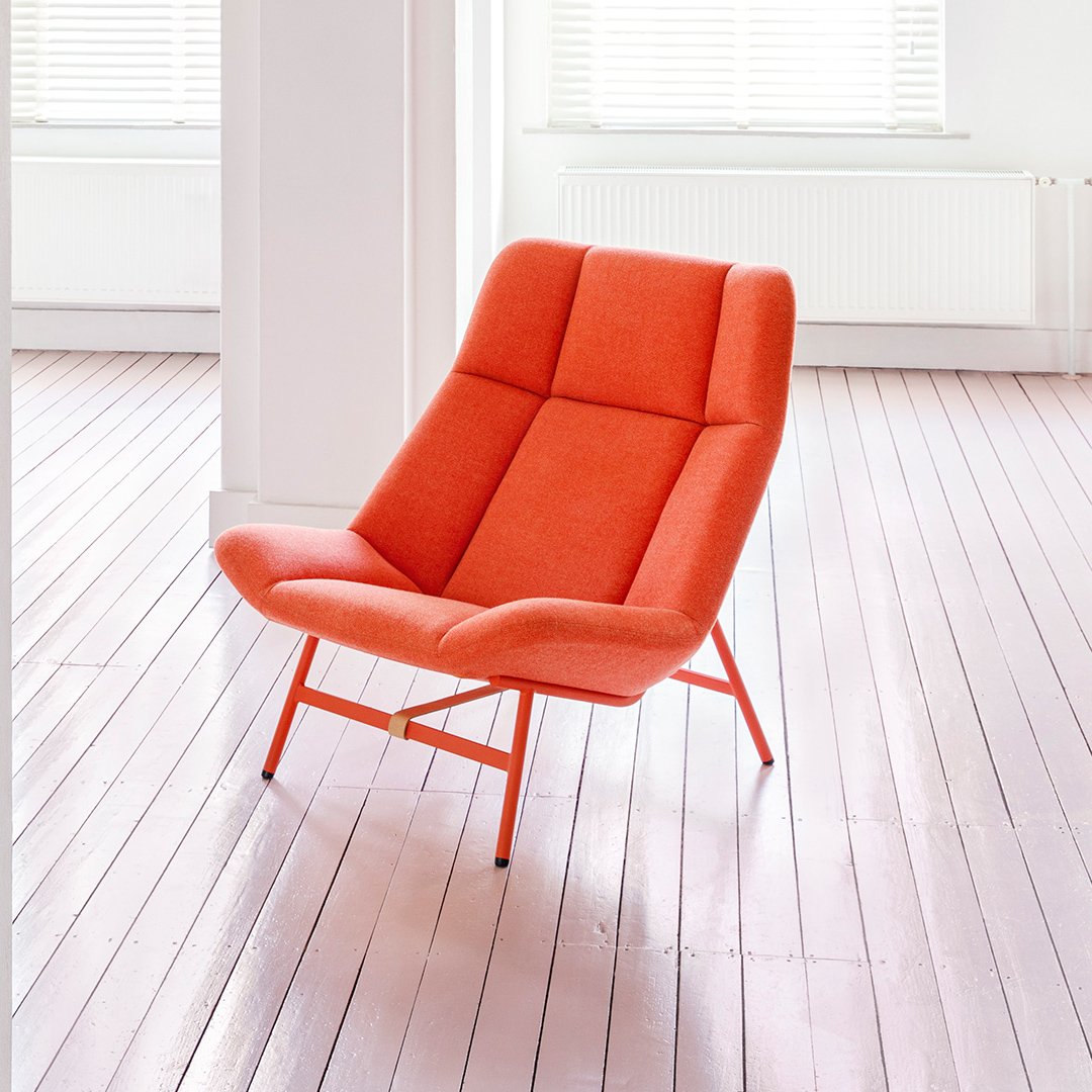 Vibrant orange accent chair with geometric pattern against a light, minimalist backdrop. Ideal for modern decor.