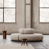 Beige circular sofa with smooth, minimalist design in a neutral-toned, modern interior setting.
