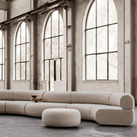 Beige modular sofa with smooth curves and soft, minimalist design in a spacious, natural light setting.
