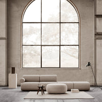 Beige modular sofa with rounded shapes, soft textures, and neutral-toned decor in a bright, airy space.