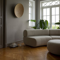 Beige sectional sofa with curved shapes, featuring a neutral color palette and natural wood flooring.