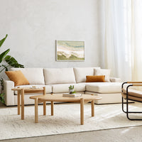 Neutral beige sectional sofa with orange accent pillows, light wooden tables, and a soft cream area rug.