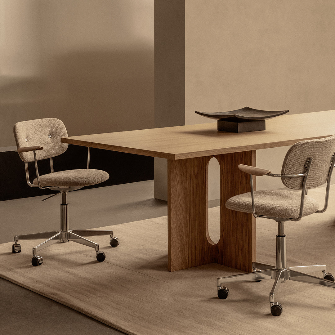 Modern wooden table with light beige fabric chairs, set against soft earth-toned walls and a neutral rug.