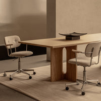 Modern wooden table with light beige fabric chairs, set against soft earth-toned walls and a neutral rug.