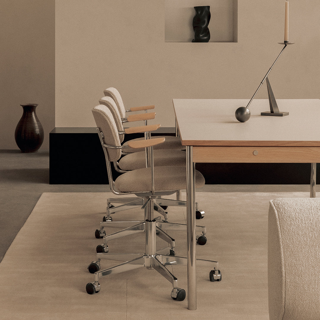 Modern workspace featuring soft beige upholstered chairs and a sleek wooden table on a neutral-toned floor.