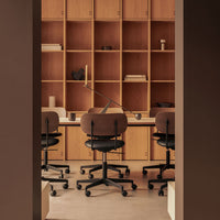 Brown office chairs with soft curves against a warm wood shelving unit, creating a modern, inviting workspace aesthetic.