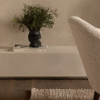 Textured cream rug, black sculptural vase, and soft beige tones create a warm, modern aesthetic in home decor.