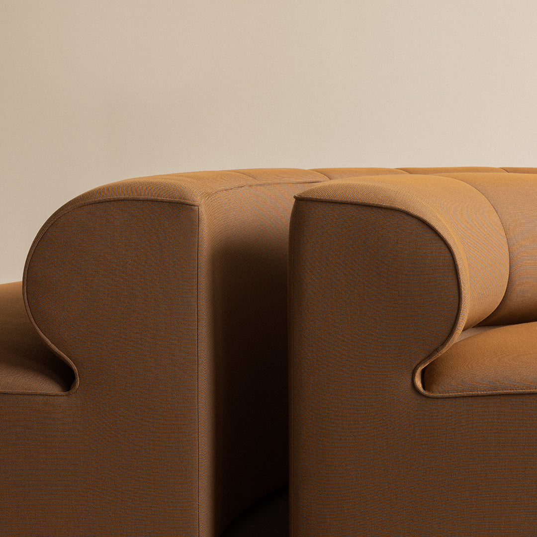 "Close-up of curved brown sofa arms with a smooth texture, showcasing a modern design."