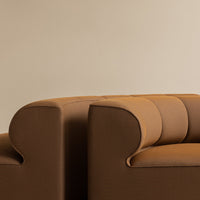 Warm brown upholstered sofa with soft curved edges and vertical seam patterns, ideal for modern interiors.