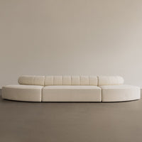Curved cream sofa with subtle quilted pattern, minimalist design, and smooth texture on a neutral background.
