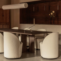 Round white chairs with textured upholstery surround a sleek dark wood table in a warm, minimalist dining room.