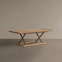 Natural wood finish dining table with a minimalist design, showcasing light beige tones and smooth, sleek lines.