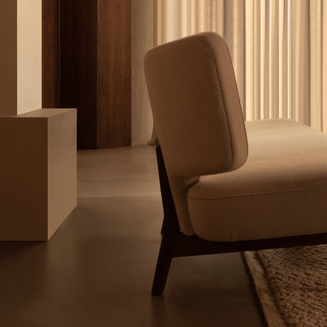 Modern beige upholstered sofa with a rich brown wooden frame, complemented by earthy tones and soft textures.