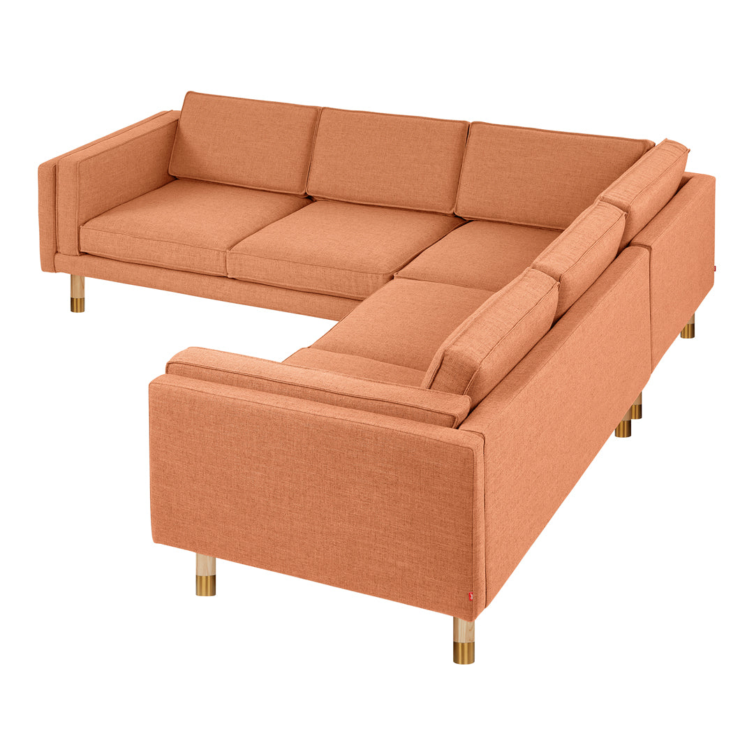 Light coral sectional sofa with a modern design, featuring a solid fabric and minimalist gold legs.