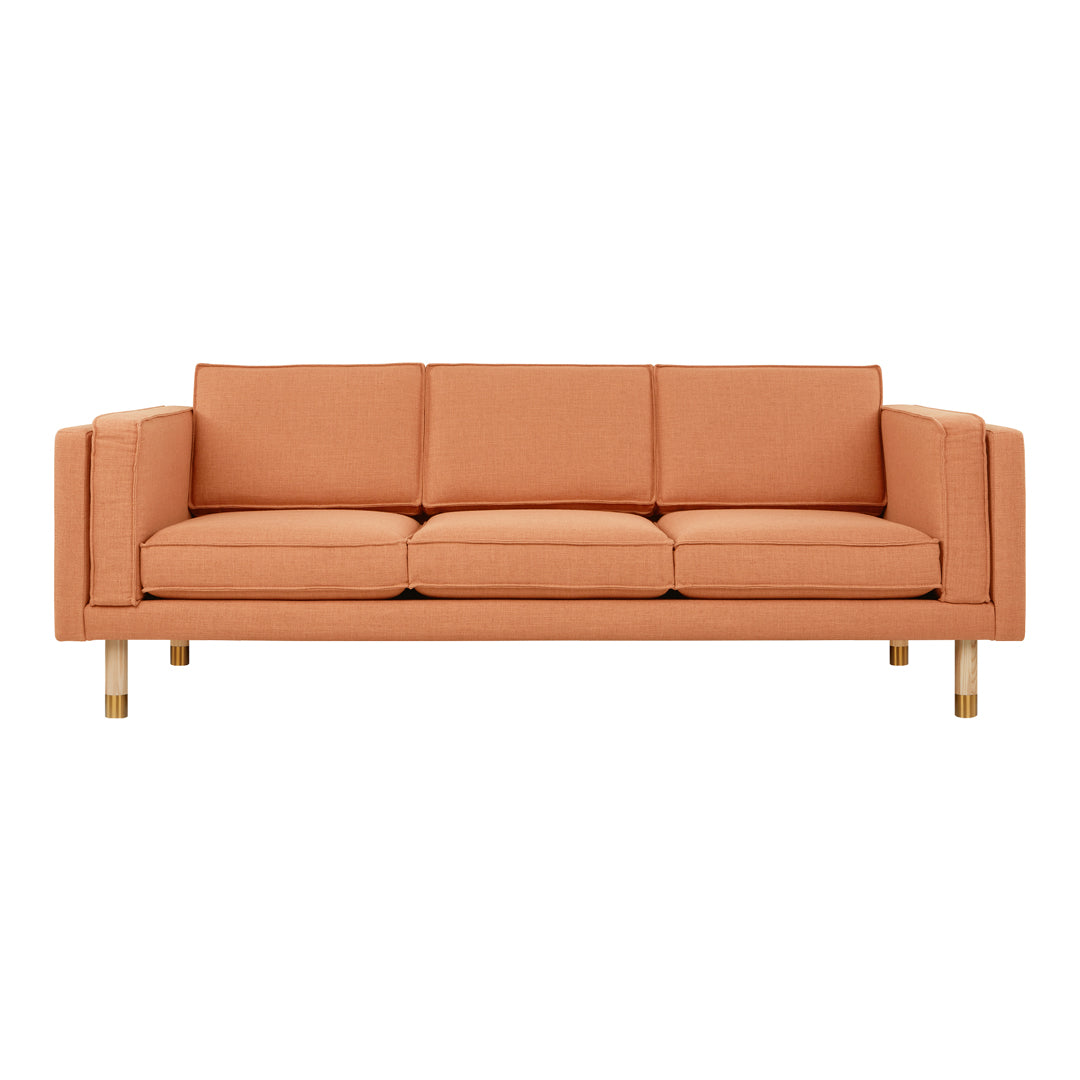 Sleek modern sofa in warm peach hue with smooth fabric and wooden legs, perfect for contemporary interiors.